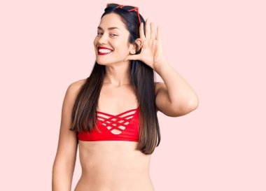 Bikini giyen, ağzı kulaklarında gülümseyen, dedikodu ve dedikodulara kulak misafiri olan güzel beyaz bir kadın. Sağırlık kavramı. 