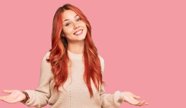 Kış süveteri giyen genç, kızıl saçlı bir kadın gülümseyerek avuçlarını açıyor, sunuyor ve reklam karşılaştırması yapıyor ve dengeyi sağlıyor. 