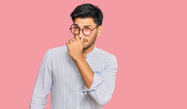 Gündelik kıyafetler ve gözlük takan genç yakışıklı bir adam pis ve iğrenç bir koku alıyor. Nefesini burnunda tutuyor. Kötü kokuyor. 