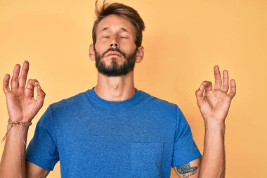 Sakallı, sıradan giyinmiş, yakışıklı beyaz adam rahatla ve parmaklarıyla meditasyon hareketi yaparken gözleri kapalı gülümse. yoga konsepti. 