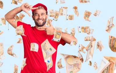 Genç, sarışın, tişört ve şapka giyen, gülümseyen, elleri ve parmakları gülen yüzlü bir adam. yaratıcılık ve fotoğrafçılık kavramı.