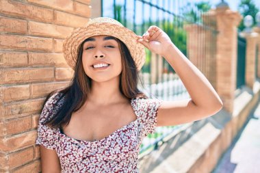 Tatildeki genç Latin kadın gülümsüyor. Şehrin duvarına yaslanmaktan mutlu..