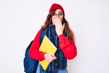 Kış eşarbı takan genç, güzel bir kadın ve sırt çantası taşıyan, ağzı ağızla kaplı bir kitap tutan, şaşırmış ve hata yapmaktan korkan bir kadın. şaşırmış ifade 
