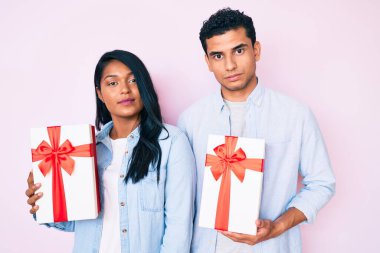 Güzel, genç, Latin bir çift yıldönümü kutlaması için hediye taşıyor. Düşünme tavrı ve kendine güvenen ayık bir yüz ifadesi. 