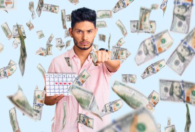 Yakışıklı Latin Amerikalı genç adam kalp takvimiyle kamerayı işaret ediyor ve sen kendine güvenen ciddi görünüyorsun.