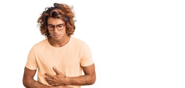 Genç İspanyol bir adam günlük kıyafetler giyiyor ve elleri karnında gözlük takıyor çünkü mide bulantısı, acı verici bir hastalık kendini iyi hissetmiyor. Ağrı kavramı. 