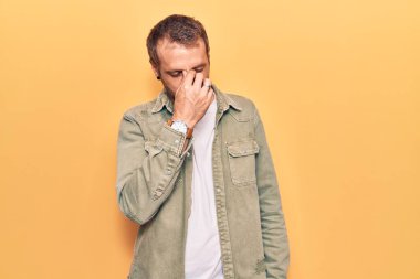 Gündelik kıyafetler giyen genç yakışıklı adam yorgun burnu ve gözleri ovuşturup yorgun ve baş ağrısı çekiyor. Stres ve hüsran kavramı. 