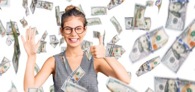 Sarı saçlı, iş kıyafetleri giymiş, gözlüklü, altı numaralı parmaklarıyla işaret eden, kendinden emin ve mutlu güzel beyaz bir kadın..