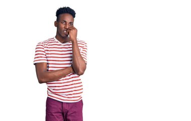 Gündelik kıyafetler giyen genç Afro-Amerikan bir adam gergin görünüyor ve elleri ağzında tırnak yiyor. anksiyete. 