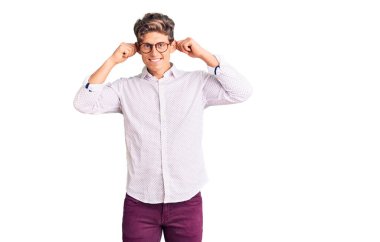 İş kıyafetleri ve gözlük takan genç yakışıklı adam gülümsüyor kulakları parmaklarıyla çekiyor, komik bir hareket. deneme sorunu 