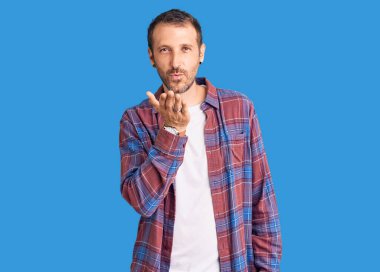 Gündelik kıyafetler giymiş genç yakışıklı bir adam kameraya bakıyor ve havada bir öpücük savuruyor. Güzel ve seksi. aşk ifadesi. 