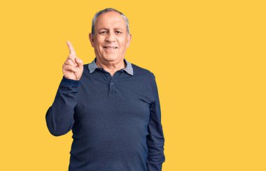 Yüzünde büyük bir gülümseme olan polo giyen yakışıklı bir adam, kameraya el ve parmak ile bakıyor.. 