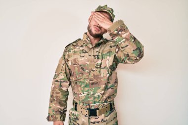 Kafkasyalı genç bir adam kamuflaj üniforması giyiyor. Elle gözlerini kapatıyor. Ciddi ve üzgün görünüyor. Görme, saklama ve reddetme konsepti 