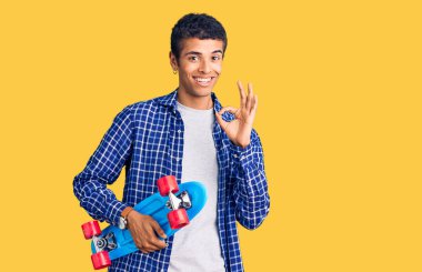 Genç Afrikalı Amerikalı adam elinde paten tutuyor. Parmaklarıyla imza atıyor, gülümsüyor. Mükemmel bir sembol. 