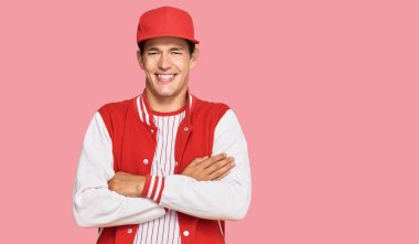 Beyzbol forması giyen yakışıklı beyaz adam kameraya bakarken kollarını kavuşturup gülümsüyor. pozitif kişi. 
