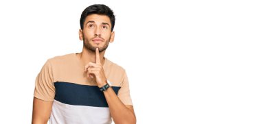 Genç, yakışıklı, günlük kıyafetler giyen, şüpheye odaklanmış, çenesinde parmak olan ve kafasını kaldırıp merak eden biri. 