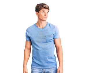 Gündelik kıyafetler giyen genç yakışıklı adam gülümseyerek yan tarafa bakıyor ve düşünüyor.. 