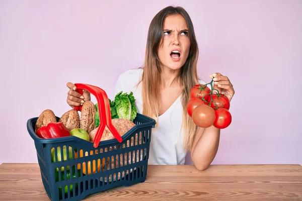 Beautiful Caucasian Woman Holding Supermarket Shopping Basket Tomatoes Angry Mad — Stock Photo, Image