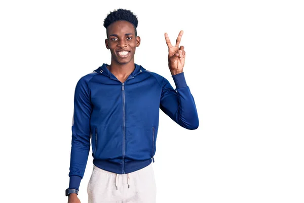 スポーツウェアを身に着けている若いアフリカ系アメリカ人の男性は 勝利のサインを行う指を示すカメラを見て笑顔 — ストック写真