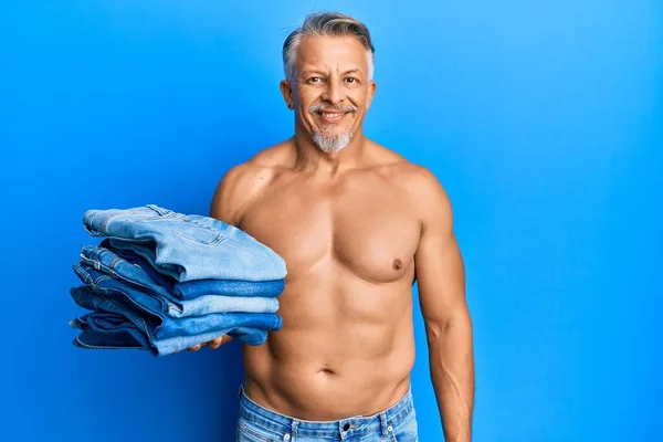 Middelbare Leeftijd Grijsharige Man Shirtloos Houden Stapel Van Gevouwen Jeans — Stockfoto