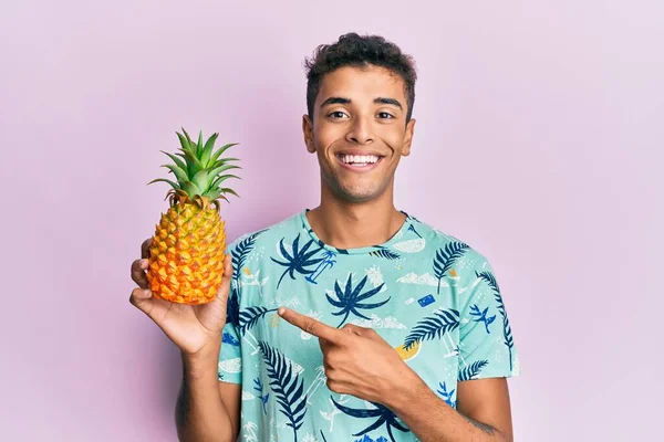Mladý Pohledný Africký Američan Muž Drží Ananas Úsměvem Šťastný Ukazující — Stock fotografie
