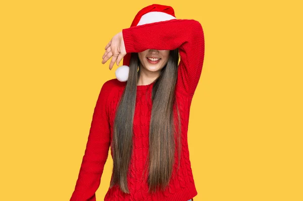 若い中国の女性は腕が陽気で面白い笑顔で目をカバークリスマスの帽子をかぶって 視覚障害の概念 — ストック写真