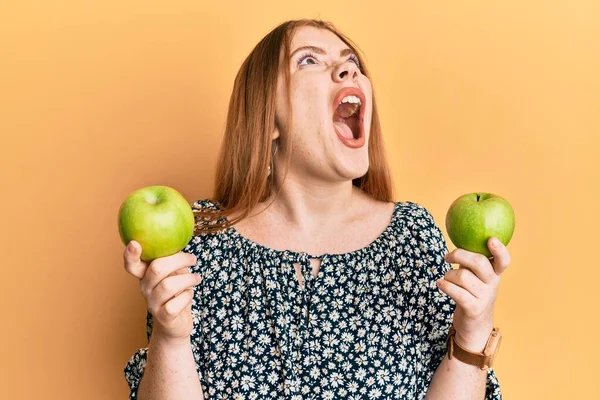 Νέα Όμορφη Κοκκινομάλλα Γυναίκα Κρατώντας Πράσινα Μήλα Θυμωμένος Και Τρελός — Φωτογραφία Αρχείου