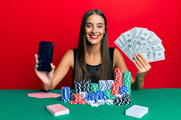 Νεαρή Ισπανίδα Που Παίζει Πόκερ Κρατώντας Smartphone Και Δολάρια Χαμογελώντας — Φωτογραφία Αρχείου