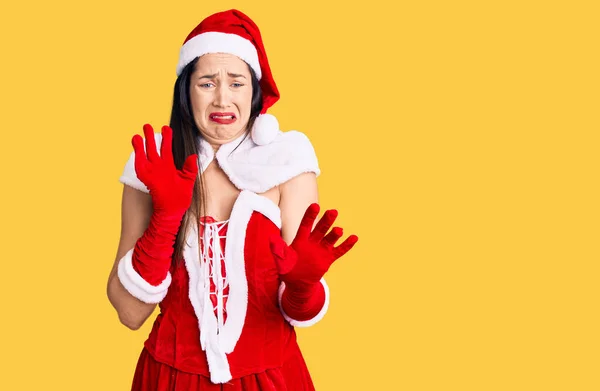 Young beautiful caucasian woman wearing santa claus costume disgusted expression, displeased and fearful doing disgust face because aversion reaction.