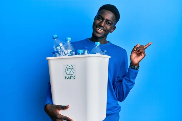 Młody Afrykański Amerykanin Trzymający Kosz Śmieci Plastikowymi Butelkami Uśmiechający Się — Zdjęcie stockowe