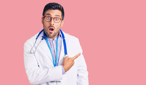 Young Hispanic Man Wearing Doctor Uniform Stethoscope Surprised Pointing Finger — Stock Photo, Image