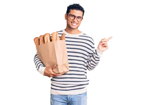 Hispano Joven Guapo Sosteniendo Bolsa Papel Con Pan Sonriendo Feliz —  Fotos de Stock