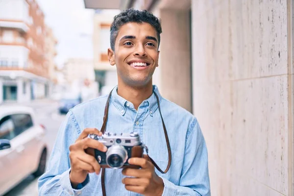 若いですラテン観光の男笑顔幸せな使用してヴィンテージカメラ歩行で街 — ストック写真