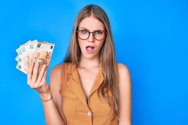 Menina Loira Jovem Segurando Notas Euro Face Choque Olhando Cético — Fotografia de Stock