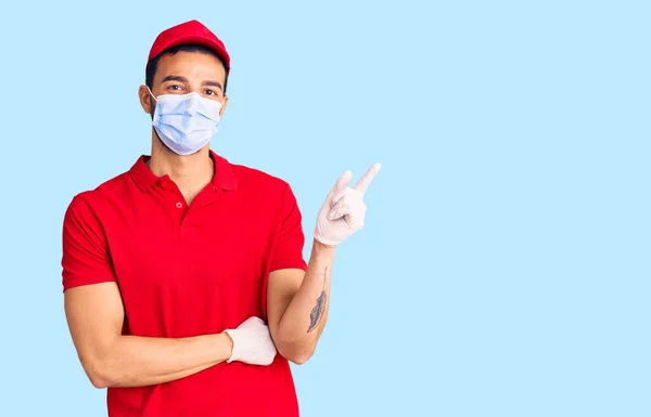 Ung Flot Spansktalende Mand Iført Levering Uniform Medicinsk Maske Smilende - Stock-foto