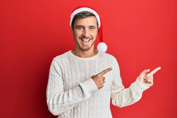 Красивый Белый Мужчина Рождественской Шляпе Улыбается Смотрит Камеру Указывая Двумя — стоковое фото