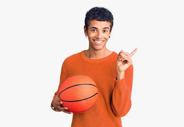 Молодой Африканский Американец Держит Баскетбольный Мяч Улыбаясь Счастливо Указывая Рукой — стоковое фото