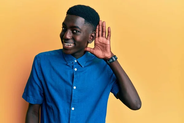 年轻的非洲裔美国人穿着休闲装 面带微笑 两手空空地听着谣言或流言蜚语 聋的概念 — 图库照片