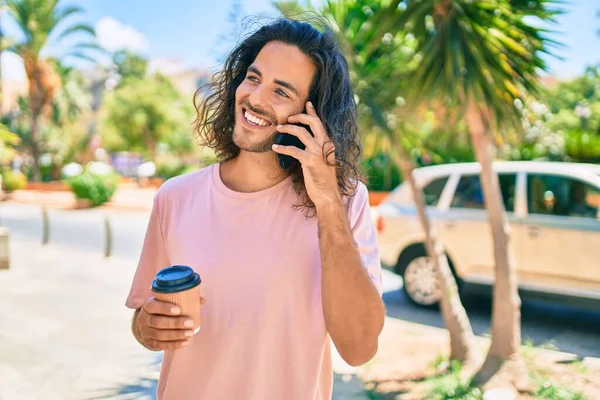 Genç İspanyol adam gülümsüyor. Akıllı telefonla konuşuyor ve şehirde kahve içiyor..