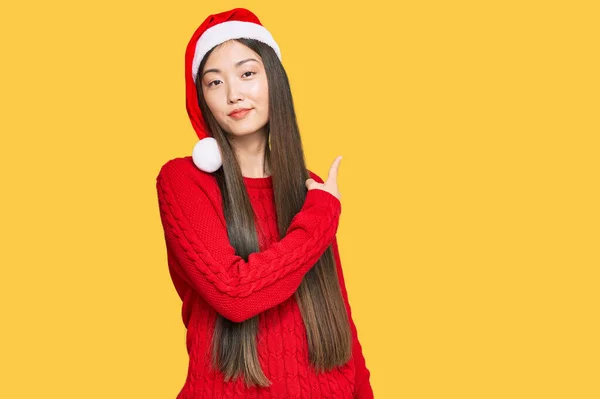 若いです中国人女性身に着けていますクリスマス帽子ポインティングとともに手指へ側ショー広告 深刻かつ穏やかな顔 — ストック写真