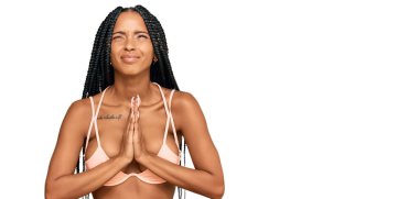 Güzel İspanyol kadın bikini giyiyor ve elleri ile yalvarıyor ve dua ediyor. Yüzünde umut ifadesi var. Duygusal ve endişeli. Yalvarıyor. 