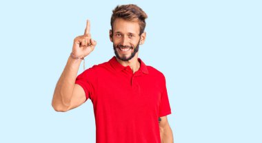 Sıradan kıyafetler giyen sakallı yakışıklı sarışın adam başarılı bir fikri işaret ediyor. Heyecanlı ve mutlu. Bir numara.. 