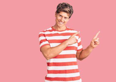 Gündelik kıyafetler giyen, gülümseyen ve kameraya bakan genç, yakışıklı bir adam.. 