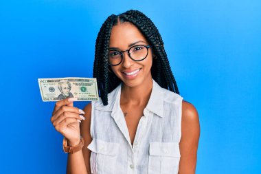 Güzel İspanyol kadın elinde 20 dolarlık banknot tutuyor. Pozitif ve mutlu görünüyor. Kendine güvenen bir gülümsemeyle dişlerini gösteriyor. 