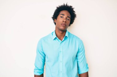 Afro saçlı, sıradan kıyafetler giyen, yüzünde ciddi bir ifadeyle rahatlamış yakışıklı Afro-Amerikan bir adam. Basit ve doğal bir şekilde kameraya bakıyorsun.. 