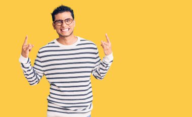 Sıradan kıyafetler ve gözlük takmış İspanyol yakışıklı genç adam çılgın bir ifadeyle bağırıyor elleri havada rock sembolü yapıyor. Müzik yıldızı. ağır kavram. 