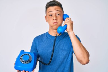 Antika telefon tutan genç İspanyol çocuk komik yüzlü yanakları şişiriyor. Ağzı havayla şişer, havayı yakalar.. 