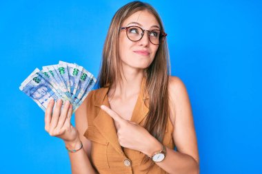 Güney Afrika rand banknotlarını tutan genç sarışın kız gülümsüyor ve başka tarafa bakıyor.. 