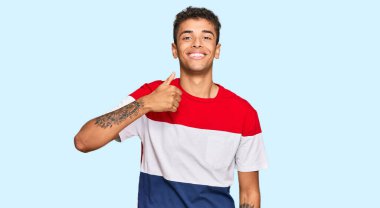 Genç, yakışıklı, Afro-Amerikan bir adam günlük giysiler giyip mutlu bir el hareketi yapıyor. Kameraya bakıp başarıyı gösteren ifade. 