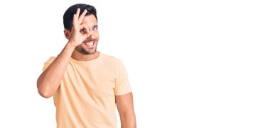 Gündelik kıyafetler giyen genç İspanyol adam el hareketleriyle gülümsüyor ve mutlu yüzüyle parmaklarından bakıyor.. 